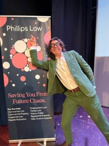 Tom Gilbey pointing at the Phillips Law banner enthusiastically.